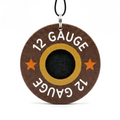 A round wooden charm designed to look like a 12 gauge shotgun shell, with a black primer center, gold ring, and orange stars on a brown background, hanging from a black cord.