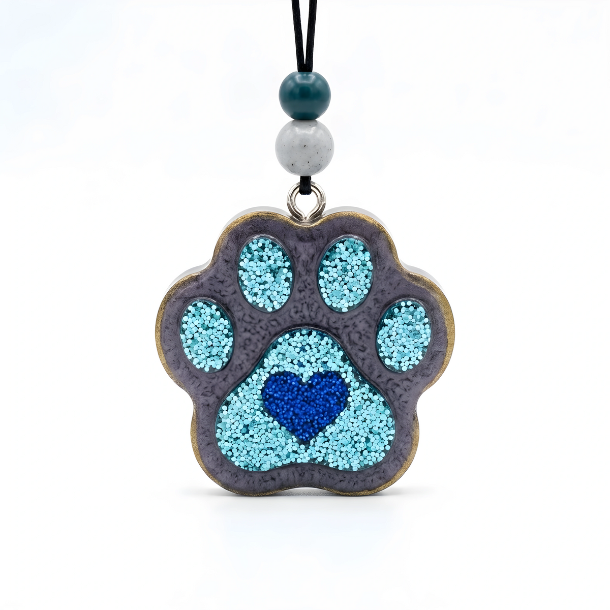 A paw-shaped pendant necklace featuring a textured gray base with light blue glitter accents and a blue heart in the center, hanging from a black cord with two decorative beads on a white background.