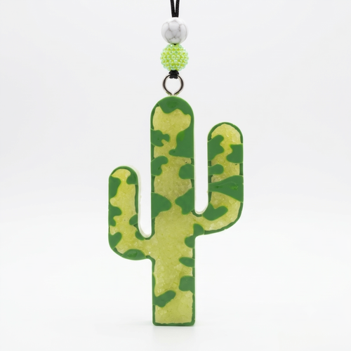A cactus-shaped keychain or bag charm with a green and yellow camouflage pattern, hanging from a black cord with decorative beads on a white background.