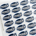 A sheet of repeated Hiser Customs logo decals or stickers on a white backing, photographed at a slight angle on a white background.