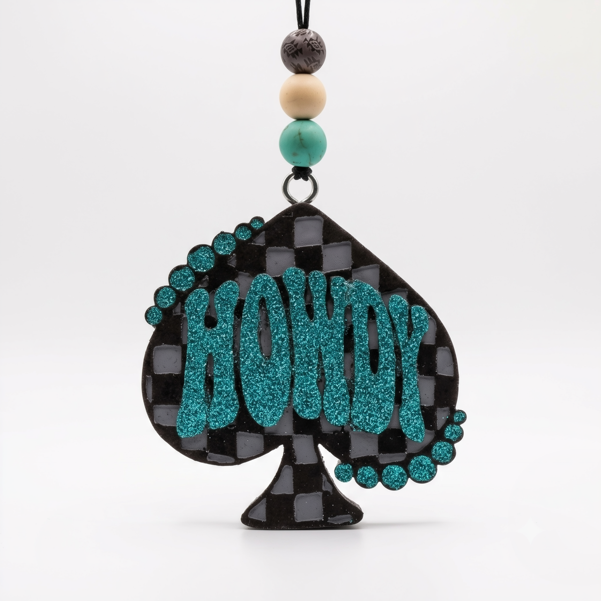 A black and teal checkered spade-shaped ornament with the word "HOWDY" in glittery teal letters, hanging from a beaded cord on a white background.