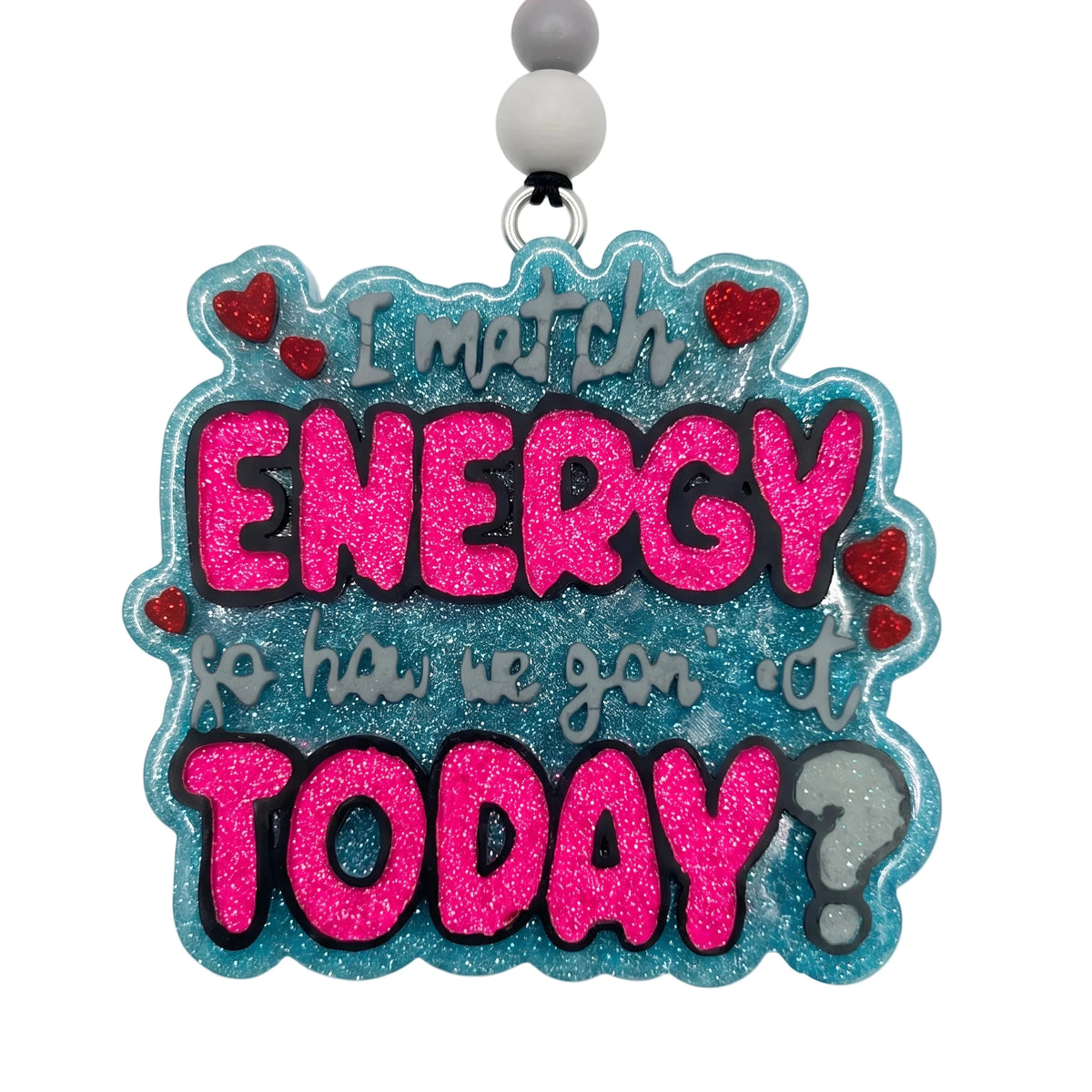 A square-shaped glitter charm with a black hanging loop and three beads (pink, gray, white). The charm features the text 'I match ENERGY so how we go on it TODAY?' in pink glitter and gray script, accented with small red hearts and a gray question mark, on a white background.