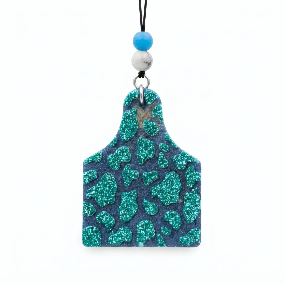 A rectangular acrylic pendant charm with a glittery teal and navy blue leopard print pattern, hanging from a black cord with blue and white beads on a white background.
