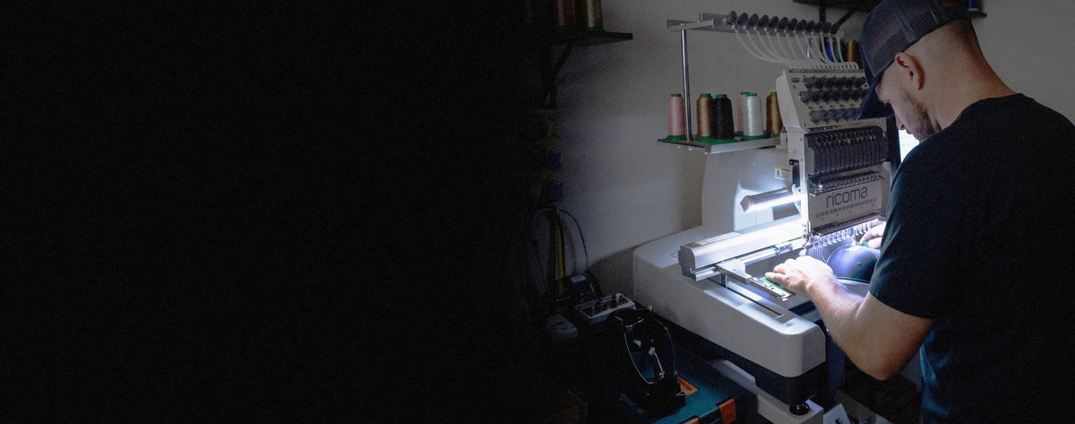 Thomas stitching a cap on the Ricoma in the Le Grand shop